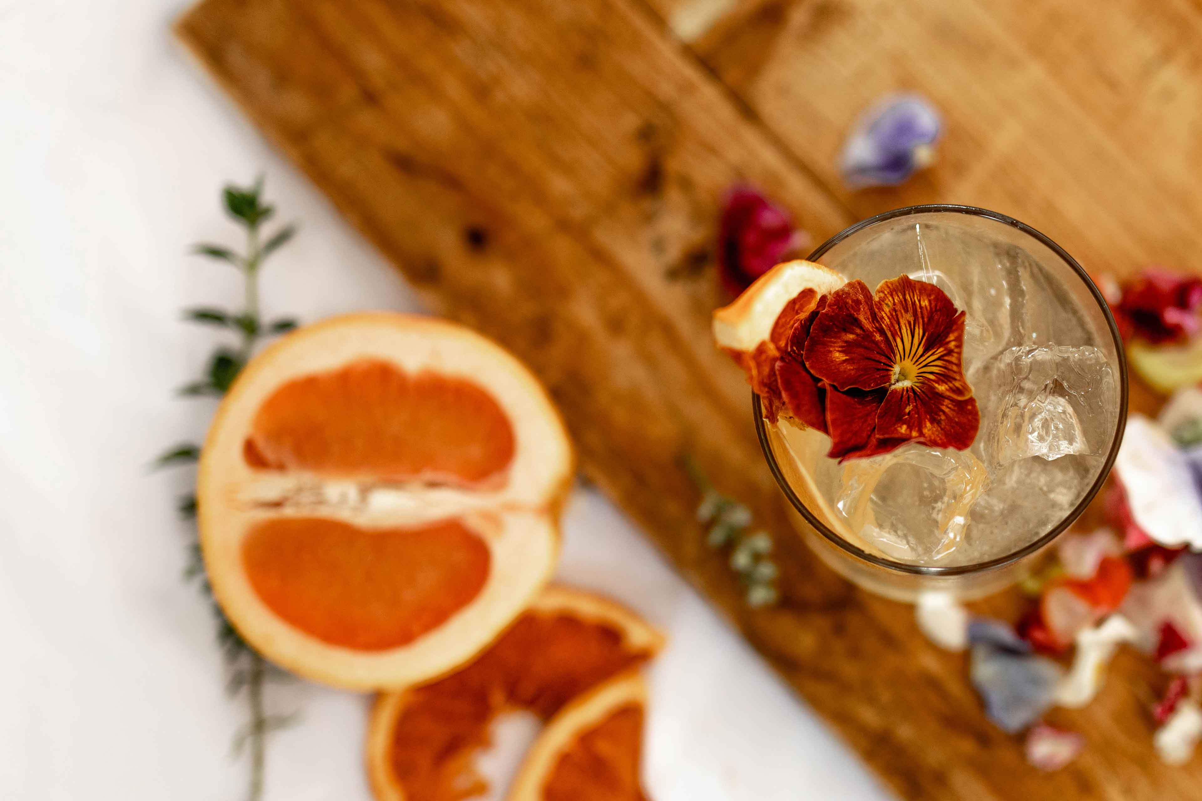 cocktail served on a wood table with some orange as garnish c