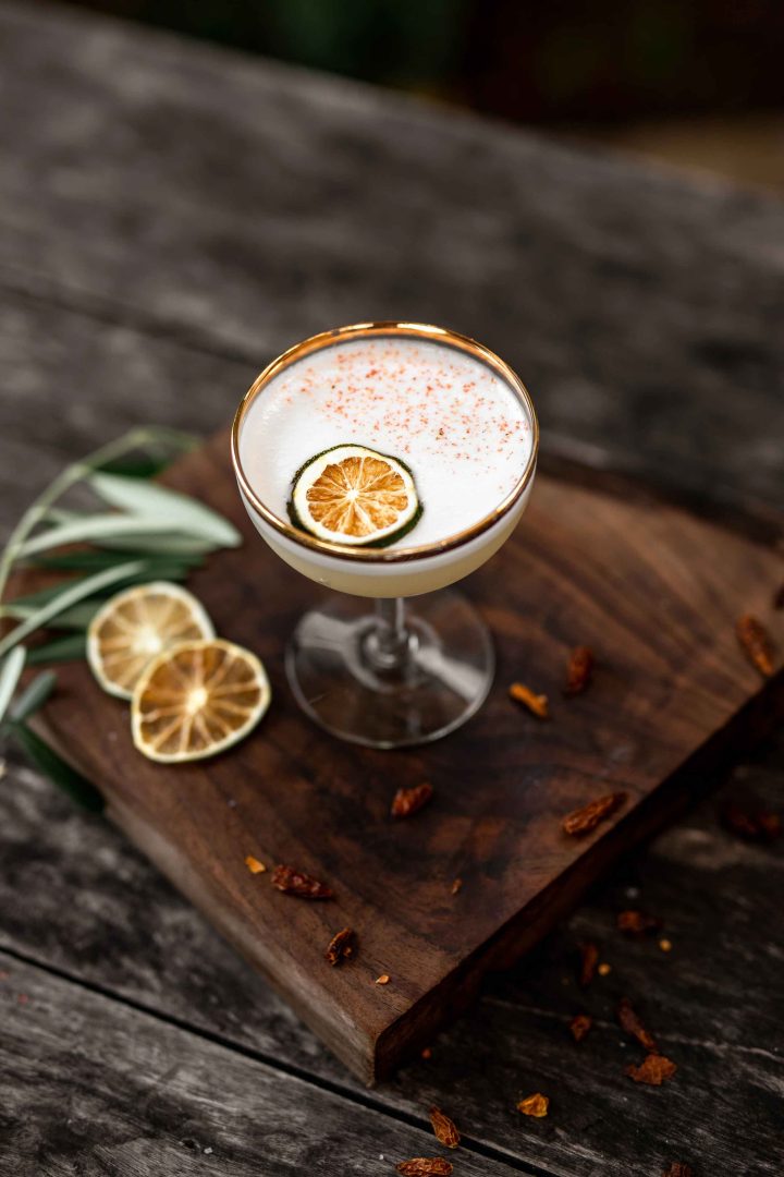Gold rimmed cocktail glass on a wooden board with citrus garnishes