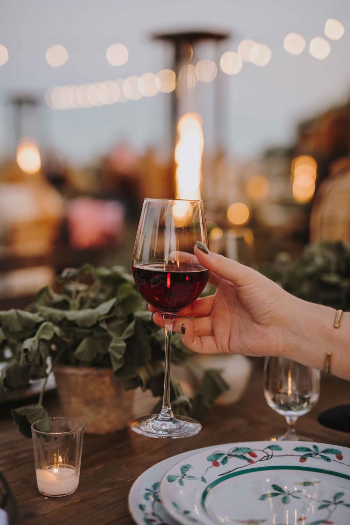 Wine glass lifted to cheers over a set dining table outside